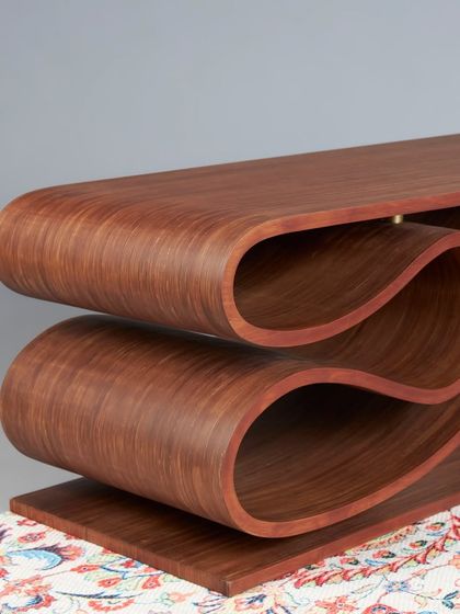 The undulating form of the bench creates interesting negative spaces and a sense of movement, making it a captivating piece from every angle.