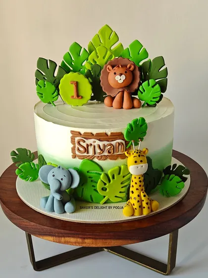 One of my most requested designs, this jungle theme cake for a first birthday features a lion, giraffe, and elephant surrounded by vibrant green leaves.