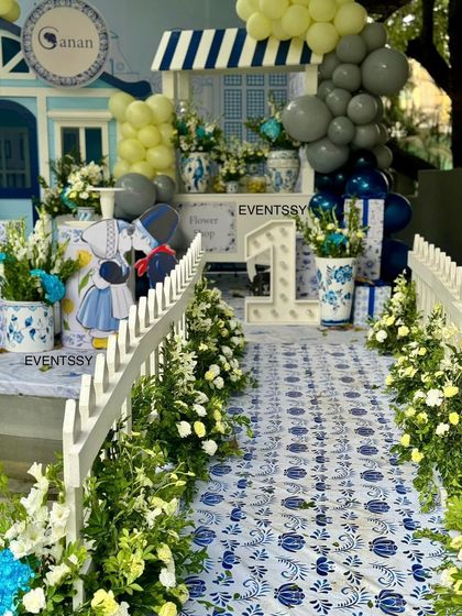 The entrance walkway for the Delft Blue party, featuring a custom-printed floor, white picket fences, and fresh flowers.