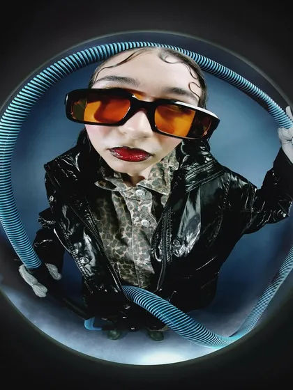An intense close-up within the fisheye frame, where the model looks directly at the viewer. The distorted perspective makes the gaze even more powerful.