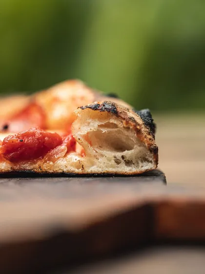 A close-up of our 72-hour fermented sourdough crust. See those air pockets? That's the secret to a light, airy, and crispy bite with a delicious tangy flavor.