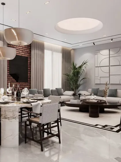 The dining area in this residence features a substantial marble-top table that seats ten, positioned under contemporary pendant lights. The design is complemented by an exposed brick wall and large art pieces, creating a stylish setting for shared meals.