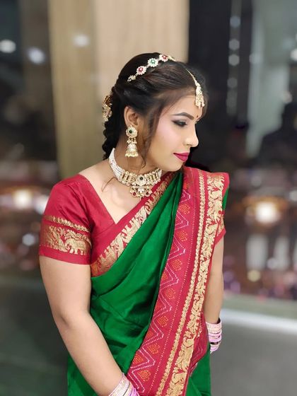 A side profile of a South Indian inspired look, featuring a beautiful green and red silk saree.