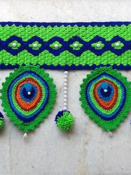 A straight-on view of the peacock toran, highlighting the geometric pattern on top and the detailed feathers below.