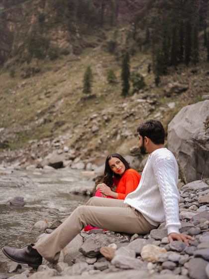 A serene moment shared by the couple, sitting by a rocky stream in the beautiful landscape of Manali.