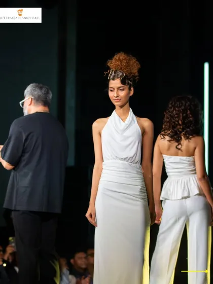 A candid moment on stage with the models. This shows the final looks, including a creative curly updo and a chic peplum top with matching pants, just before the final walk.