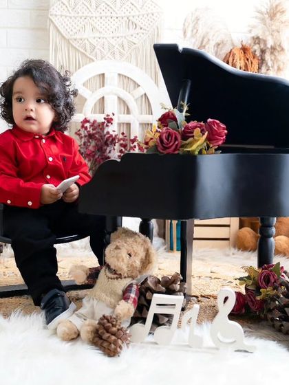 A little musician in red. This toddler looks so focused and adorable sitting at the miniature piano in this classic, rustic setup.