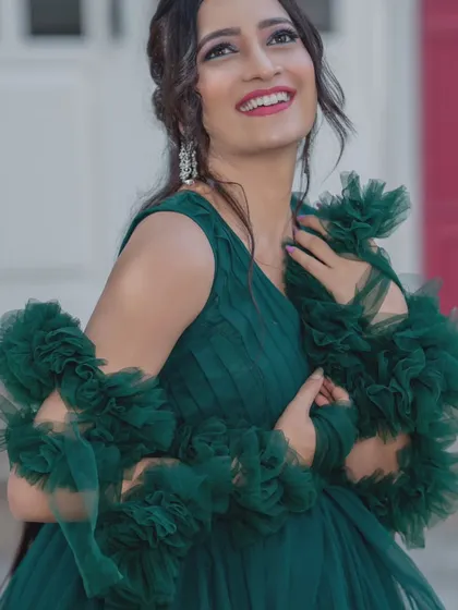 A close-up of the model in the emerald green gown, showing her joyful expression and the elegant makeup.
