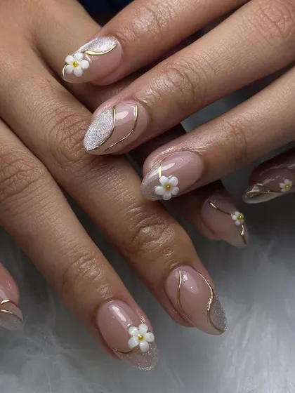 Nude nails with a touch of white glitter, delicate 3D daisies, and fine gold line work. This set is all about elegance and intricate details.