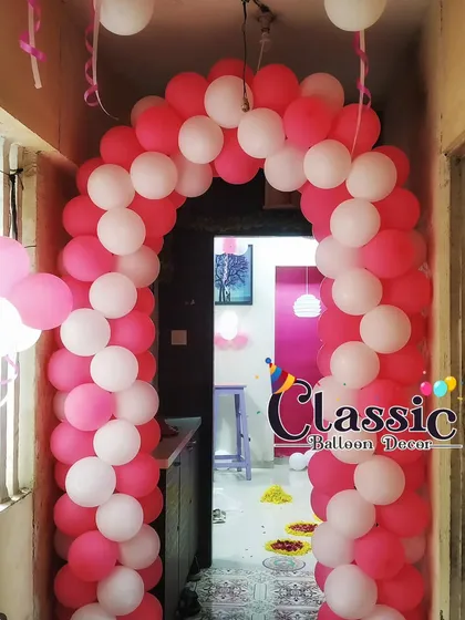 A classic pink and white balloon gate to decorate the entrance of a home for a baby girl's welcome party.