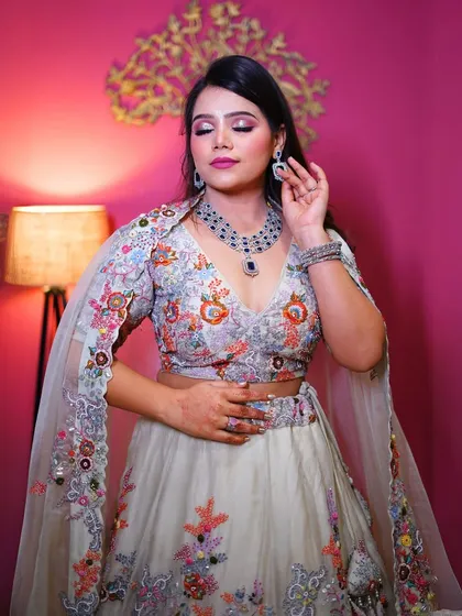 This white lehenga with colorful floral embroidery is perfect for a day wedding or spring-themed shoot. The cape-style dupatta adds a modern twist.
