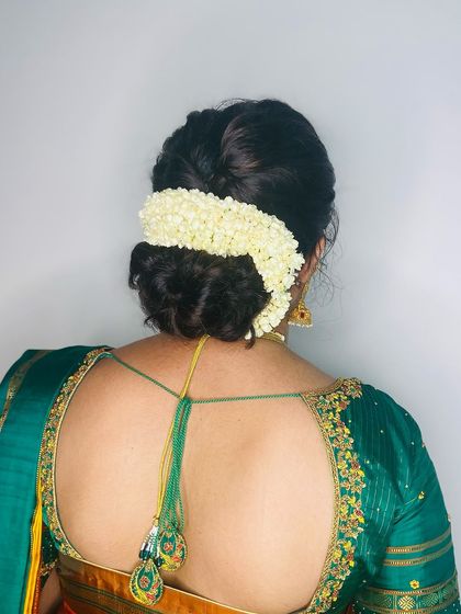 A simple and elegant messy bun adorned with a string of fresh jasmine flowers (mallige). This is a classic choice for any traditional South Indian event.
