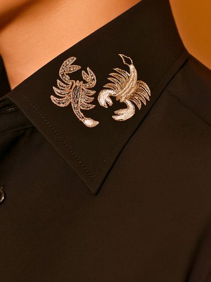 For those with a bolder edge, we offer unique motifs like these scorpions embroidered in silver thread on the collar of a crisp black shirt.