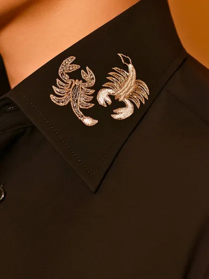 For those with a bolder edge, we offer unique motifs like these scorpions embroidered in silver thread on the collar of a crisp black shirt.