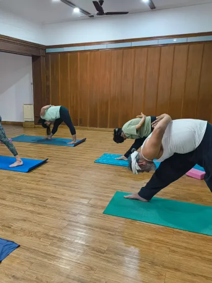 Change happens when we learn to surrender. Students in a group class practicing Parsvottanasana (pyramid pose), finding a deep stretch and release.
