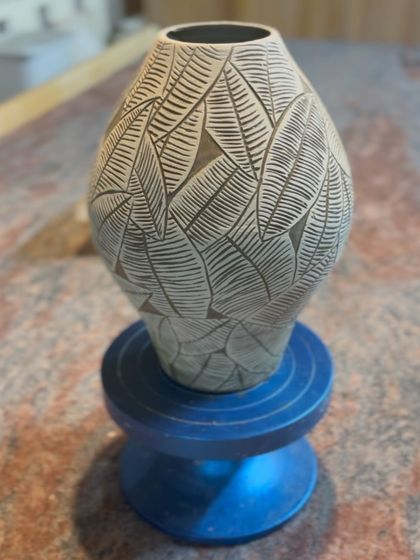 A closer look at a sgraffito vase with a leaf motif. The contrast between the dark clay body and the light-colored slip makes the hand-carved details pop.