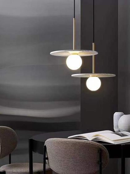 A minimalist pendant with a flat marble disc and a glowing globe. This design is perfect for adding a touch of sophistication over a dining table or reading nook.