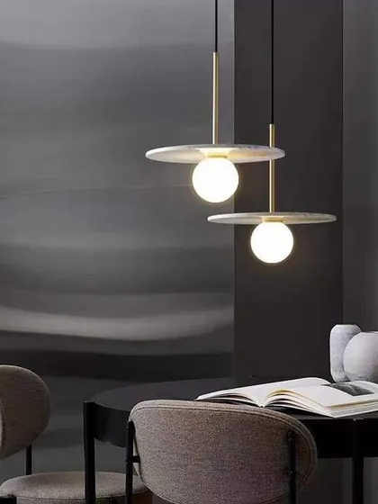 A minimalist pendant with a flat marble disc and a glowing globe. This design is perfect for adding a touch of sophistication over a dining table or reading nook.