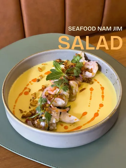 Our Seafood Nam Jim Salad, a dish inspired by travels to Thailand. It features tender seafood in a zesty dressing over a smooth corn and coconut panna cotta.