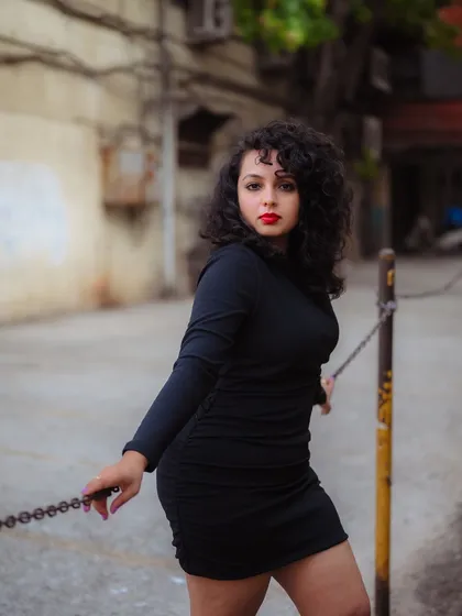 A powerful portrait using an industrial chain as a prop. The gritty background and the model's strong pose create a bold and impactful fashion statement.