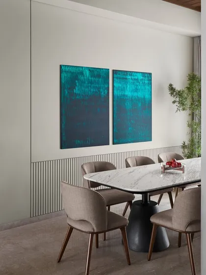 The "Hover" dining table, made of marble, steel, and concrete, is paired here with a striking teal diptych I painted. The sleek wall detailing and fluted texture add a refined visual break, creating a sophisticated and cohesive dining setting.