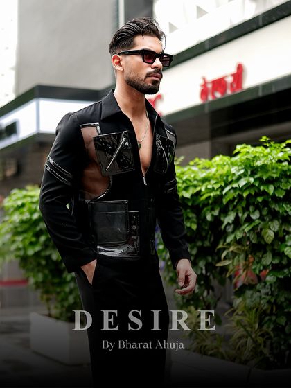 A closer look at the black utility shirt, highlighting the high-gloss PVC pockets and zipper details. It's a blend of tactical gear and high fashion.