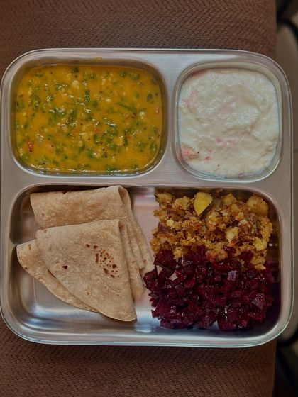 This thali includes chapati, dal methi, and a colorful mix of sautéed beetroot and potato, with a side of raita to cool the palate.