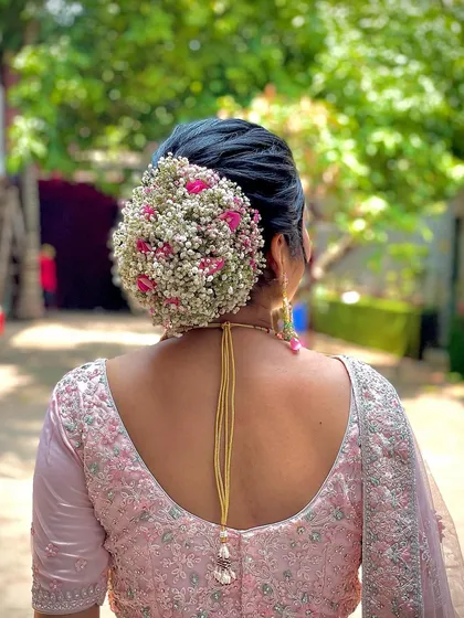 A beautiful floral bun for a wedding, using a mix of baby's breath and pink roses. This is a soft, romantic, and timeless hairstyle for any bride.