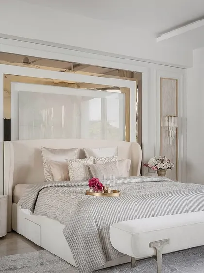 A closer look at the bed and headboard, where mirrored and upholstered panels are layered to create depth and reflect light. The wingback headboard and plush bench add a touch of classic elegance to the contemporary design.