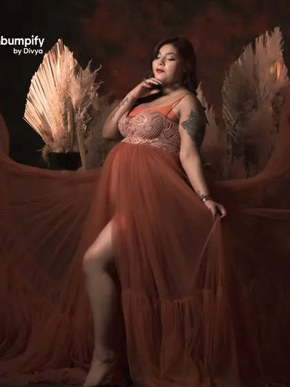 A dramatic and artistic shot from the royal throne session. The flowing fabric of her orange gown and the moody lighting create a truly breathtaking image.