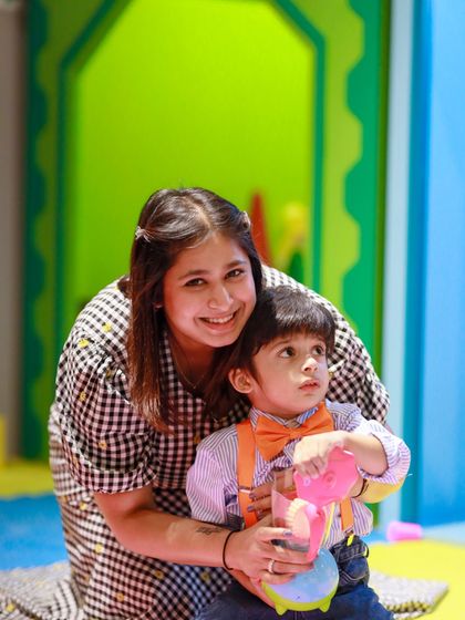 A mother helps her son, the birthday boy, during playtime. Our play area is designed for parents and children to interact and play together.