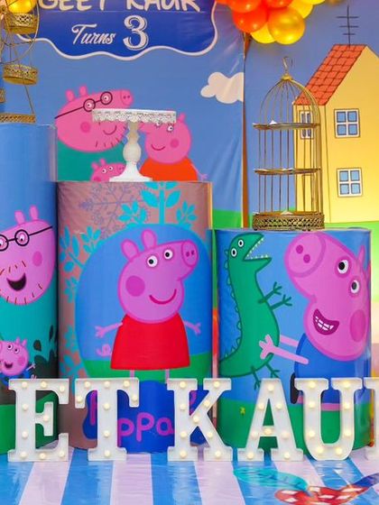 A colorful Peppa Pig-themed third birthday. The setup includes character-printed plinths, a large light-up number '3', and a 'GEET KAUR' marquee.