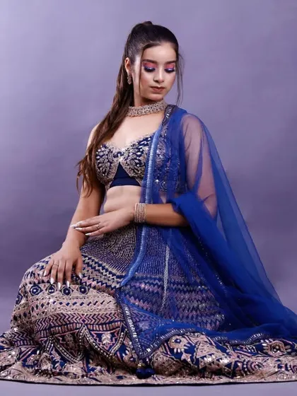 A full-length seated portrait from the same studio session. This pose elegantly displays the entire lehenga, making it suitable for both a model portfolio and a lookbook.