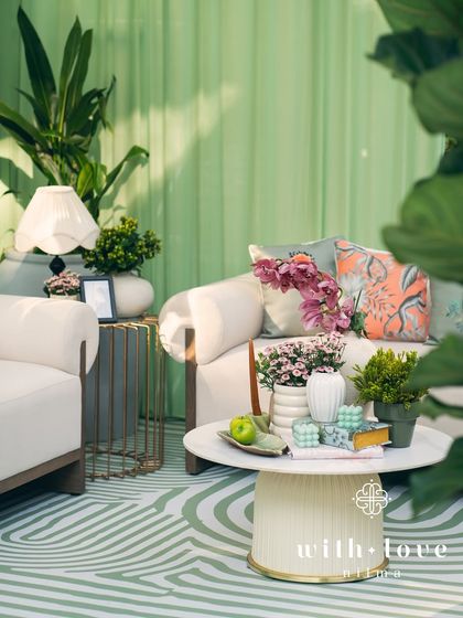 A comfortable lounge area within 'The Conservatory', featuring plush sofas, custom-printed cushions, and modern coffee tables. The space is designed to be both beautiful and inviting.