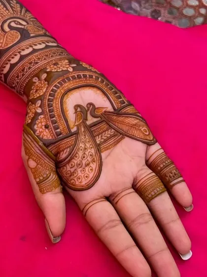 A close-up of the peacock pair on the palm, showcasing the delicate details and symmetry of the design.