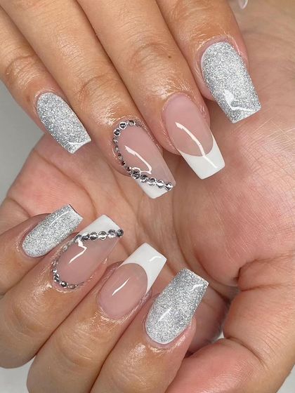 A bold and glamorous set of square extensions, featuring a mix of white French tips, full silver glitter nails, and a curved line of rhinestones.