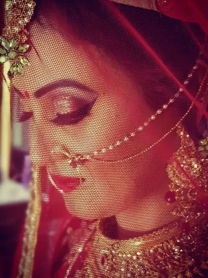 This artistic shot uses dramatic red lighting and the bride's veil to create a moody and romantic portrait. Her bold red lip and defined eyes stand out beautifully.
