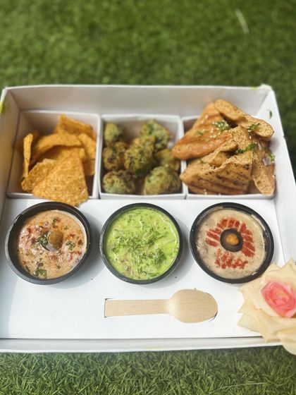A look inside the Mezze Box, showing the compartments for crackers, falafel, grilled pita, and three delicious dips.