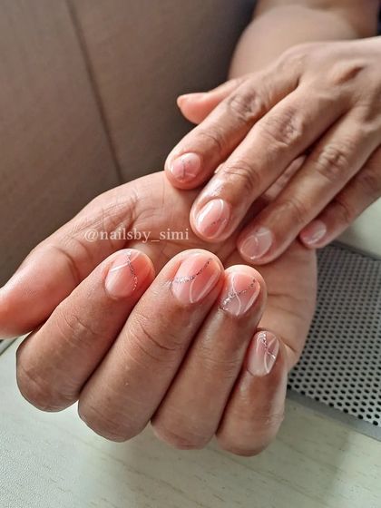 Sweet, simple, and elegant. This design on short, natural-looking nails features a sheer pink base with delicate silver glitter lines for a touch of sparkle.