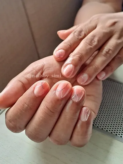 Sweet, simple, and elegant. This design on short, natural nails features a soft marble effect with delicate silver glitter lines.
