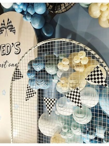 A detail shot of the race car theme, showing the custom "Ved's Fast One" arched backdrop with checkered flag pennants.