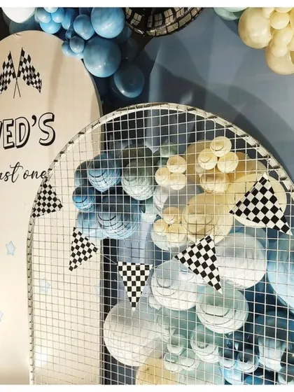 A detail shot of the race car theme, showing the custom "Ved's Fast One" arched backdrop with checkered flag pennants.