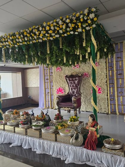 An angled perspective of the half-saree ceremony decor, highlighting the offering table with peacock and swan props.