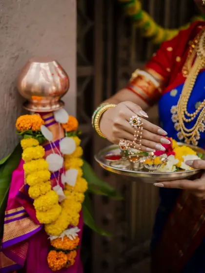 A close-up shot focusing on the details of the Gudi Padwa ritual. This image highlights the model's hands, adorned with beautiful jewelry, as she offers flowers to the Gudi, symbolizing new beginnings.
