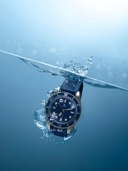A dynamic action shot of a dive watch splashing into the water. This kind of photography is technically challenging but incredibly effective for demonstrating a product's features, like water resistance.