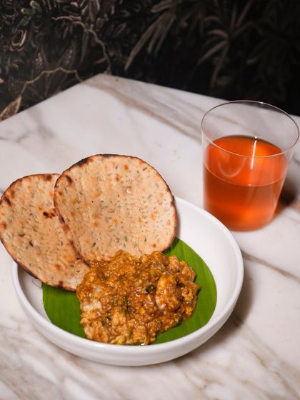Another look at our Bheja Fry with Khasta Roti, paired with a refreshing beverage. The combination of the rich, spiced main and a cool drink creates a perfectly balanced meal.
