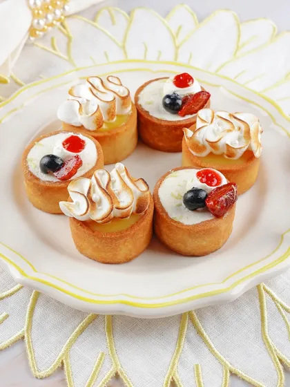 A collection of mini fruit and meringue tarts, styled for a catering company's menu to look both delicious and professional.