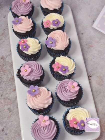 Mini chocolate cupcakes with pastel buttercream swirls and tiny flower decorations, created for the fairy garden party.