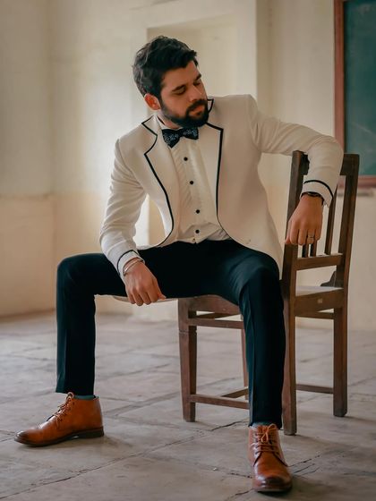 A more relaxed pose, pairing the formal jacket with casual brown boots for a stylish, high-low fashion statement.