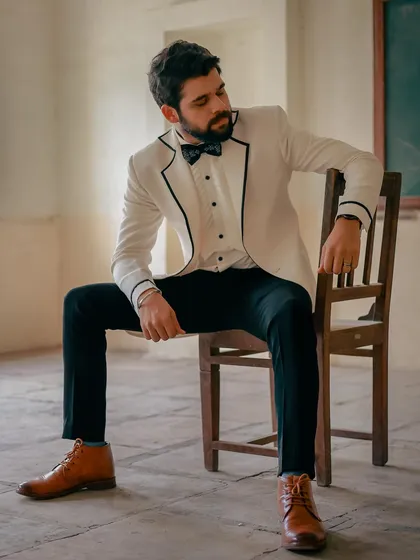 A full-length view of Kshitish Date's white tuxedo look. Paired with tan boots, it adds a contemporary, slightly rustic edge to a formal outfit.